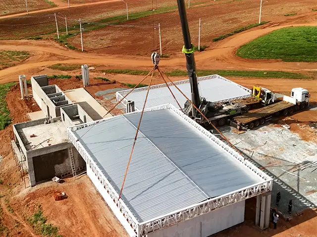 Guindaste realizando montagem de cobertura metálica em obra — NT Locação de Guindastes