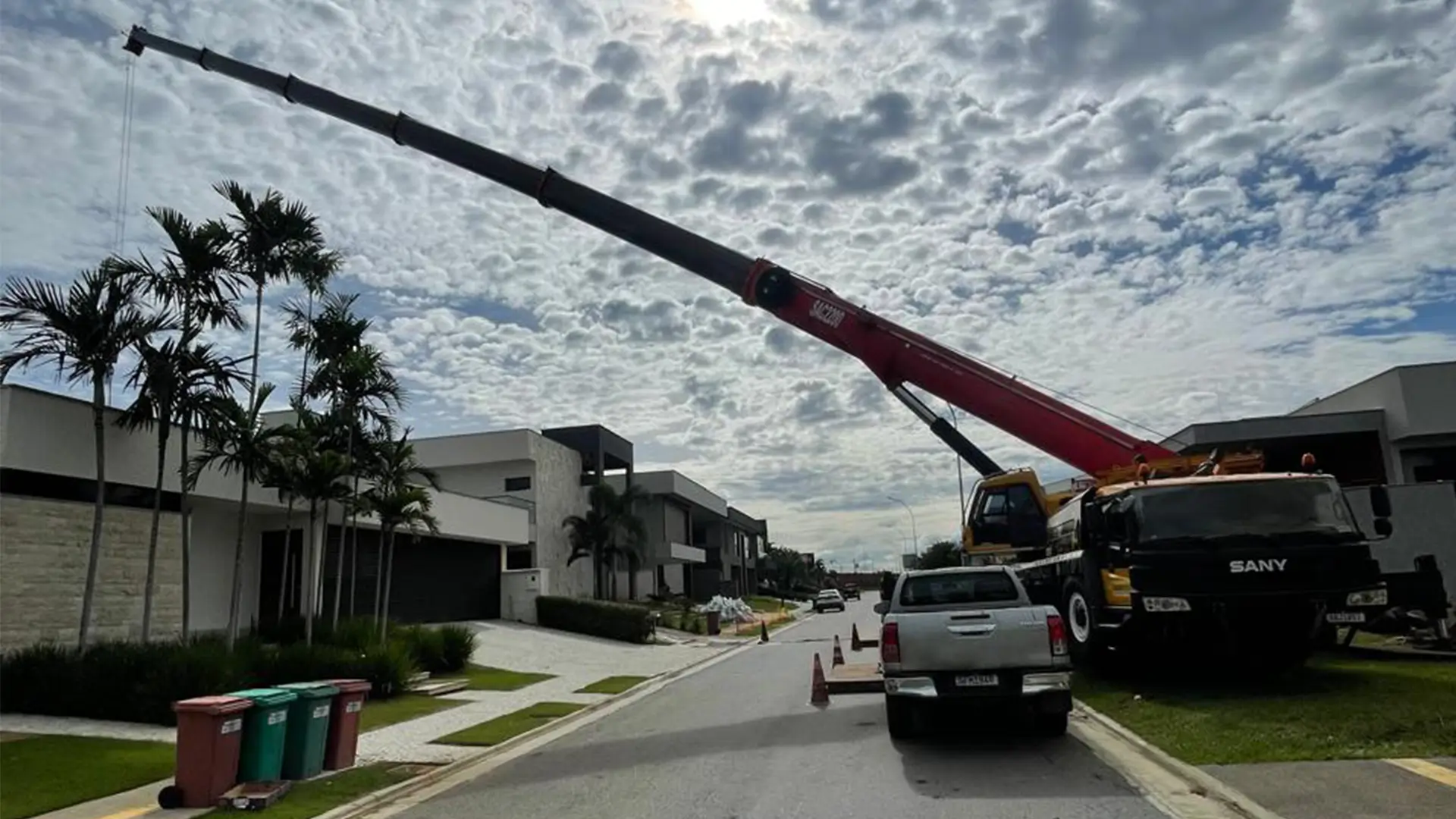 Guindaste operando em condomínio residencial para içamento de cargas em área urbana.