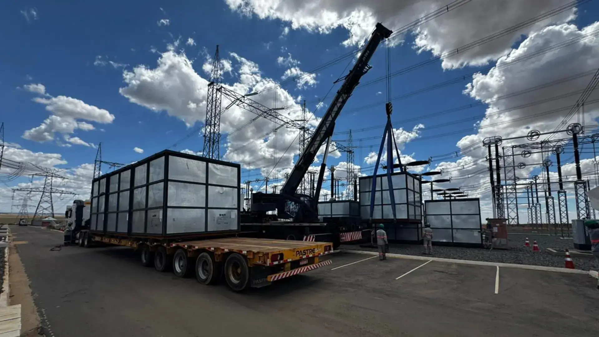 Caminhão guindaste realizando a operação segura de içamento e movimentação de equipamentos pesados em uma subestação elétrica.