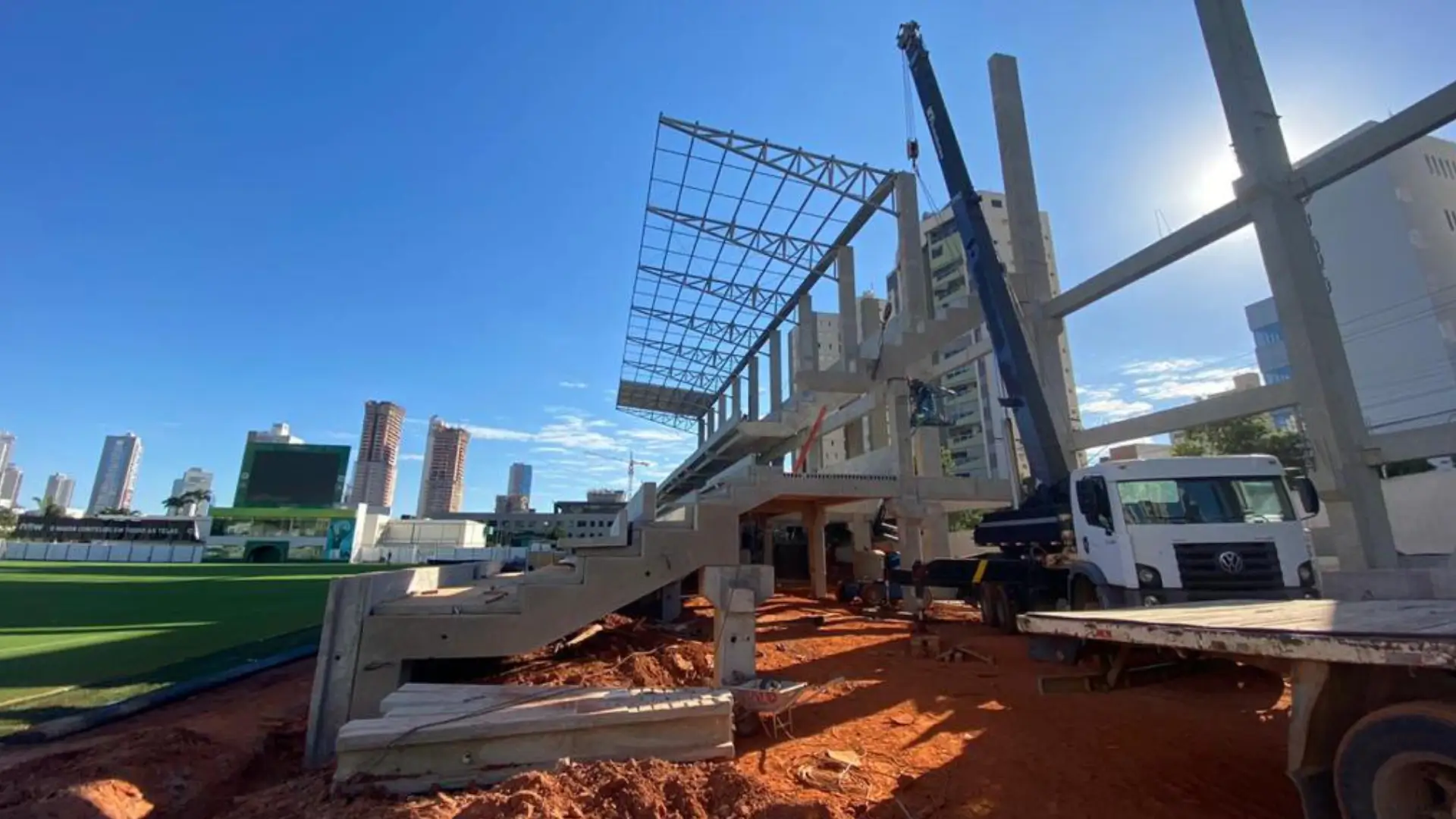 Caminhão guindaste branco da NT Locação realizando o içamento e posicionamento de pilares pré-moldados de concreto em canteiro de obras industrial